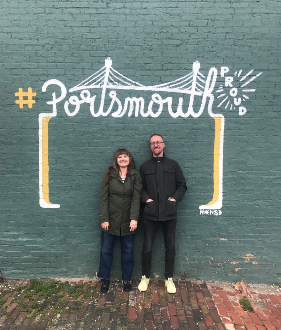 Filmmakers Amanda Page and David Bernabo stand in front of a mural that reads '#Portsmouth.' Image courtesy Amanda Page