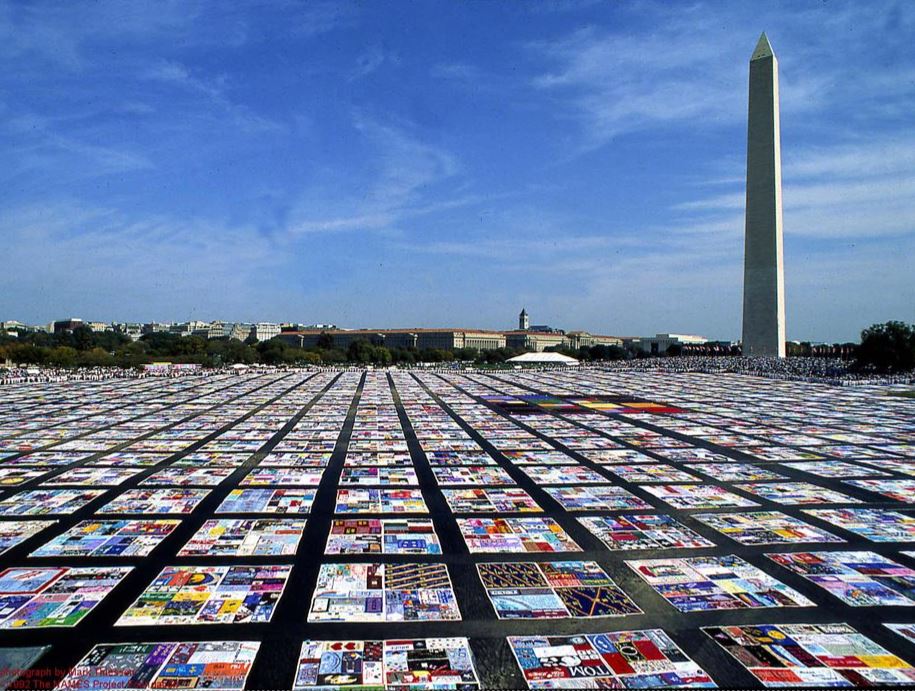 The AIDS Memorial Quilt displayed on the National Mall. In the background looms the Washington Monument and the Smithsonian museums