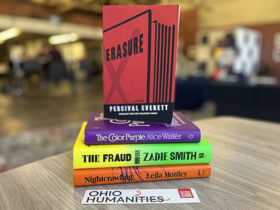 A stack of books, including Nightcrawling by Leila Mottley, The Fraud by Zadie Smith, The Color Purple by Alice Walker and, on display on top, Erasure by Percival Everett, with an Ohio Humanities bookmark in the foreground